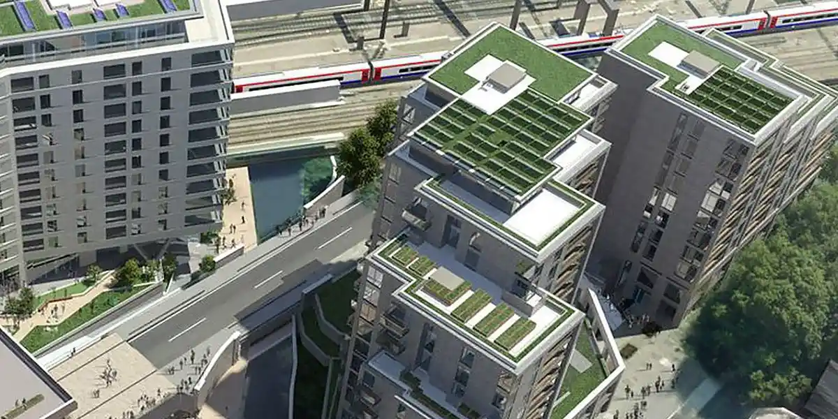 Aerial view of modern mixed-use buildings with green roofs and a train passing nearby, showcasing WiredScore Platinum certified development