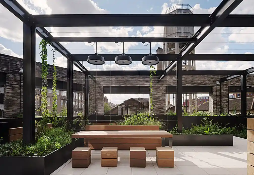 Modern outdoor communal seating area with wooden benches and planters in a mixed-use development