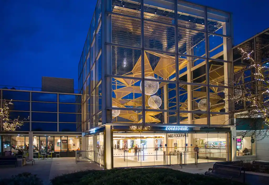 Night view of CentreMK shopping centre entrance with illuminated glass facade and modern architectural lighting