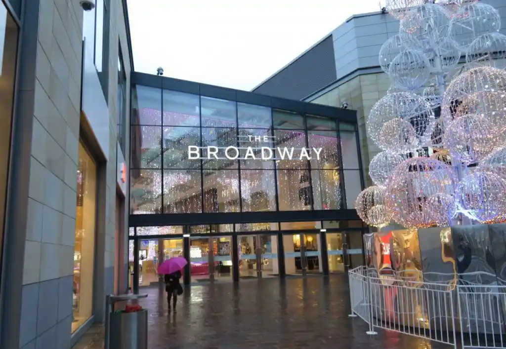 Shopping centre entrance showing glass facade, illuminated signage, and festive lighting at The Broadway